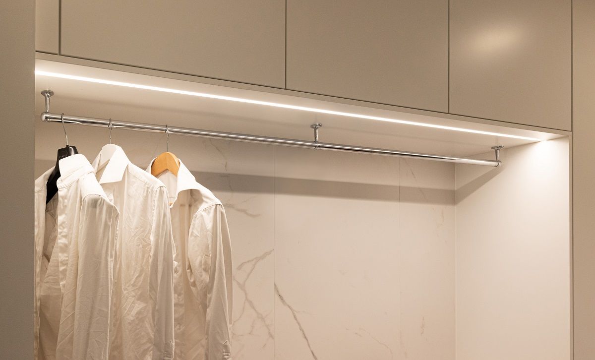 Illuminazione a strisce led in un profilo di alluminio a incasso con temperatura di colore neutra sulla parte superiore di un armadio aperto.